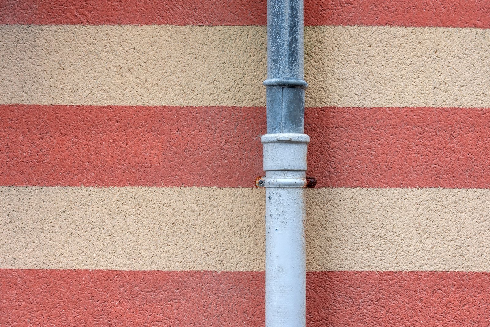Two downpipes fixed to the wall of a house