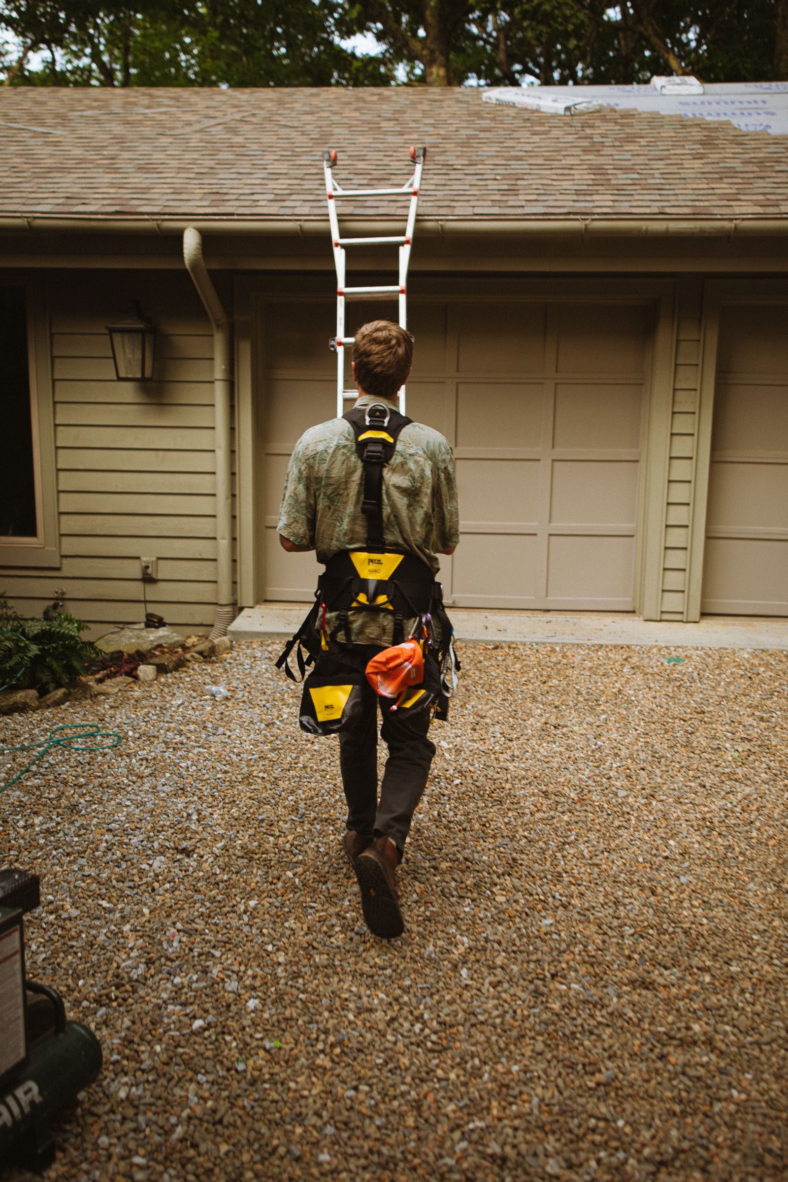 A worker carrying a ladder to a house for gutter work